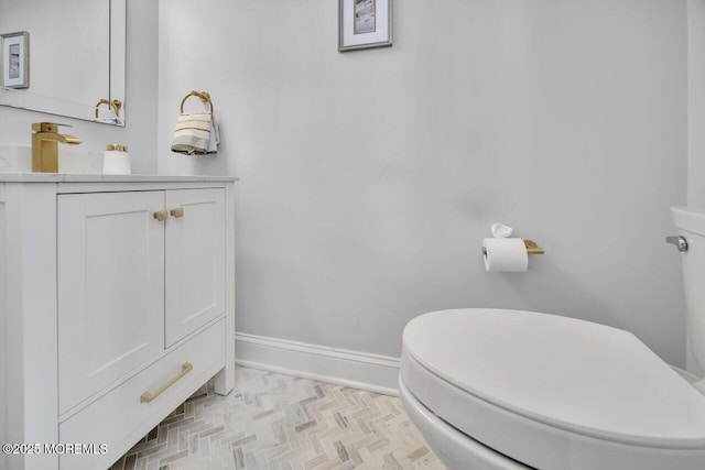 bathroom featuring vanity, toilet, and baseboards