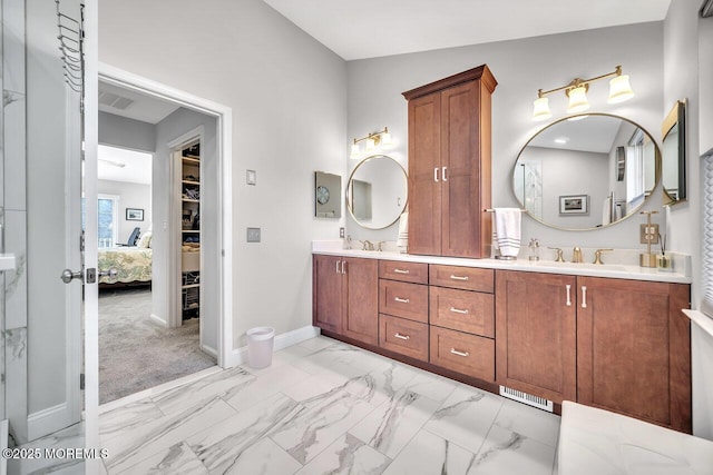 full bathroom featuring double vanity, marble finish floor, baseboards, and a sink