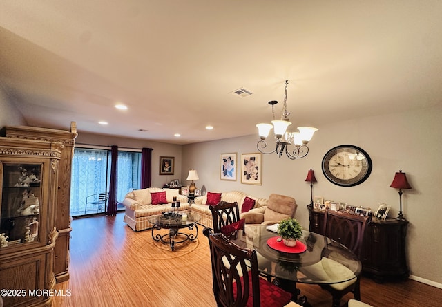 dining space with baseboards, visible vents, wood finished floors, an inviting chandelier, and recessed lighting