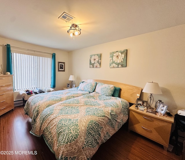 bedroom with dark wood-type flooring, baseboard heating, and visible vents