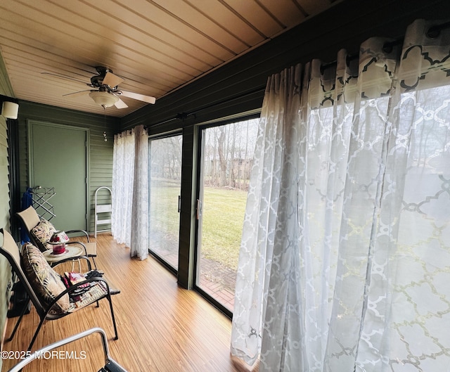 sunroom / solarium with a ceiling fan and wood ceiling