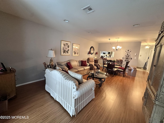 living room featuring a chandelier, visible vents, baseboards, and wood finished floors