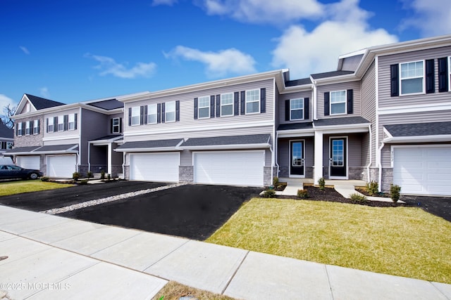 view of front of house featuring a residential view, stone siding, driveway, and an attached garage