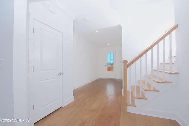 entrance foyer with light wood-type flooring, baseboards, and stairs