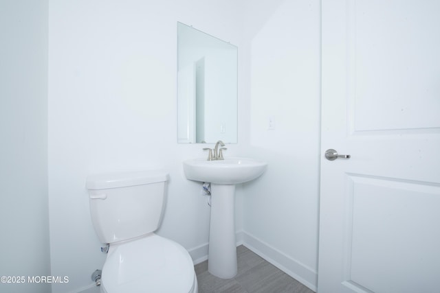 half bath with a sink, toilet, and baseboards