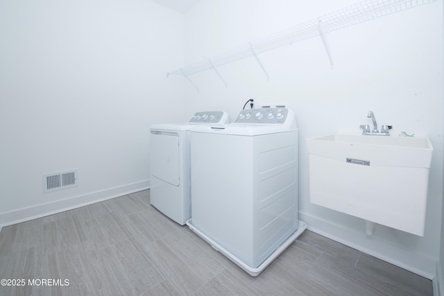 laundry area with visible vents, a sink, washer and dryer, laundry area, and baseboards