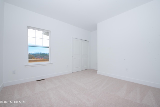 unfurnished room featuring light colored carpet, visible vents, and baseboards