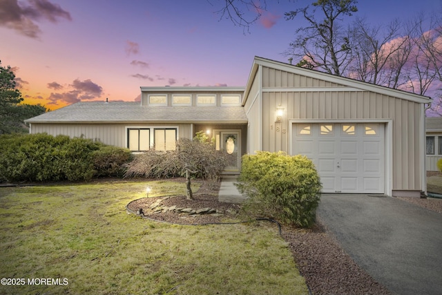 mid-century modern home with a garage, a yard, driveway, and board and batten siding