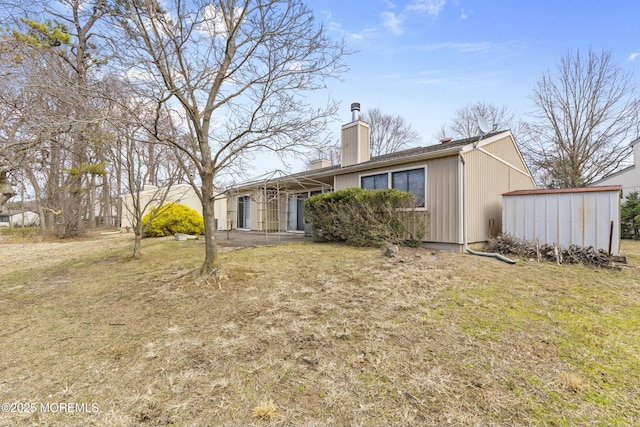 back of property with a chimney and a yard