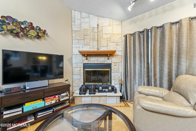 living area featuring lofted ceiling, a textured ceiling, and a stone fireplace