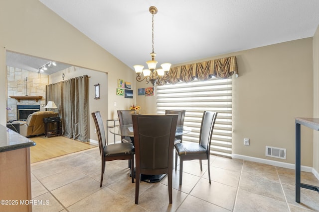 dining room with light tile patterned floors, visible vents, lofted ceiling, a fireplace, and a notable chandelier