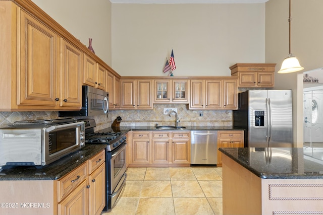 kitchen featuring a towering ceiling, backsplash, stainless steel appliances, and a sink