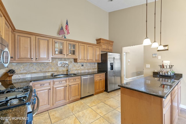 kitchen featuring tasteful backsplash, brown cabinetry, dark stone counters, appliances with stainless steel finishes, and a sink