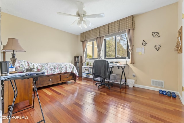 bedroom featuring visible vents, ceiling fan, baseboards, and wood finished floors