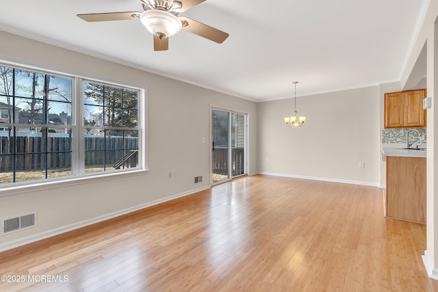 spare room with crown molding, visible vents, a sink, and light wood finished floors