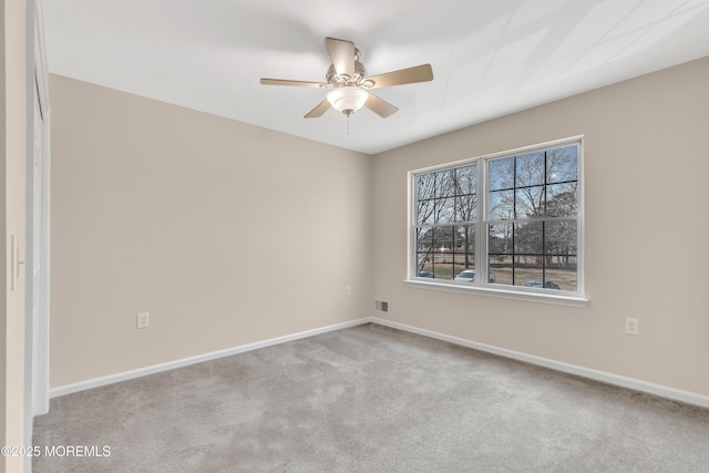 empty room with carpet floors, visible vents, ceiling fan, and baseboards