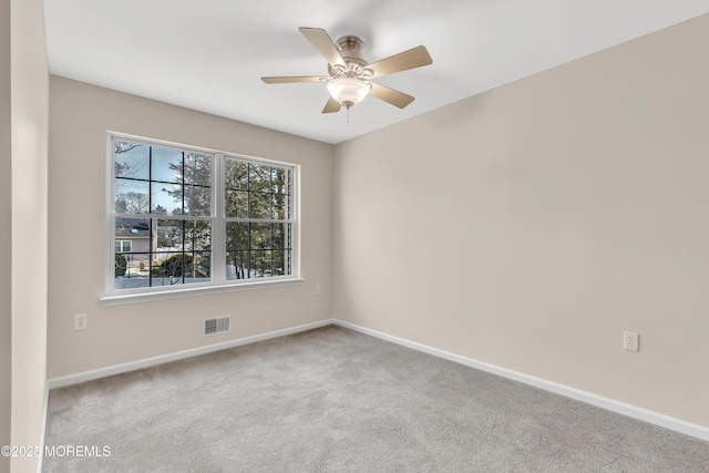 carpeted empty room featuring visible vents, ceiling fan, and baseboards