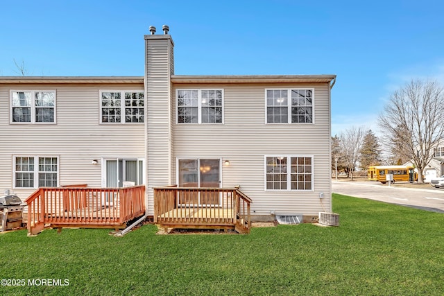 back of house with a lawn, a chimney, and a wooden deck