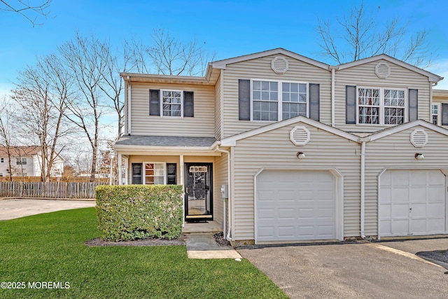 view of front of home featuring an attached garage, a front lawn, fence, and aphalt driveway