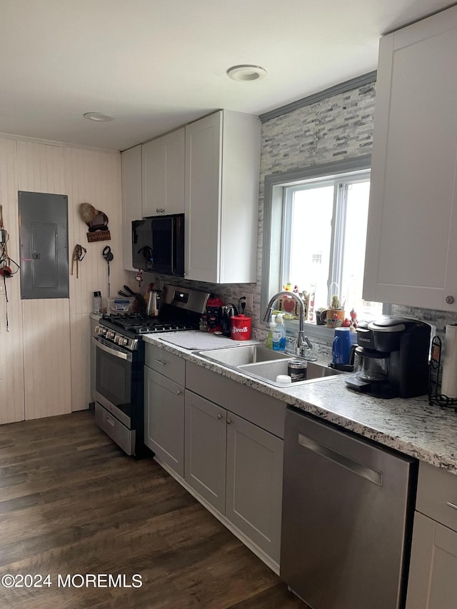 kitchen featuring stainless steel appliances, light countertops, dark wood-type flooring, a sink, and electric panel