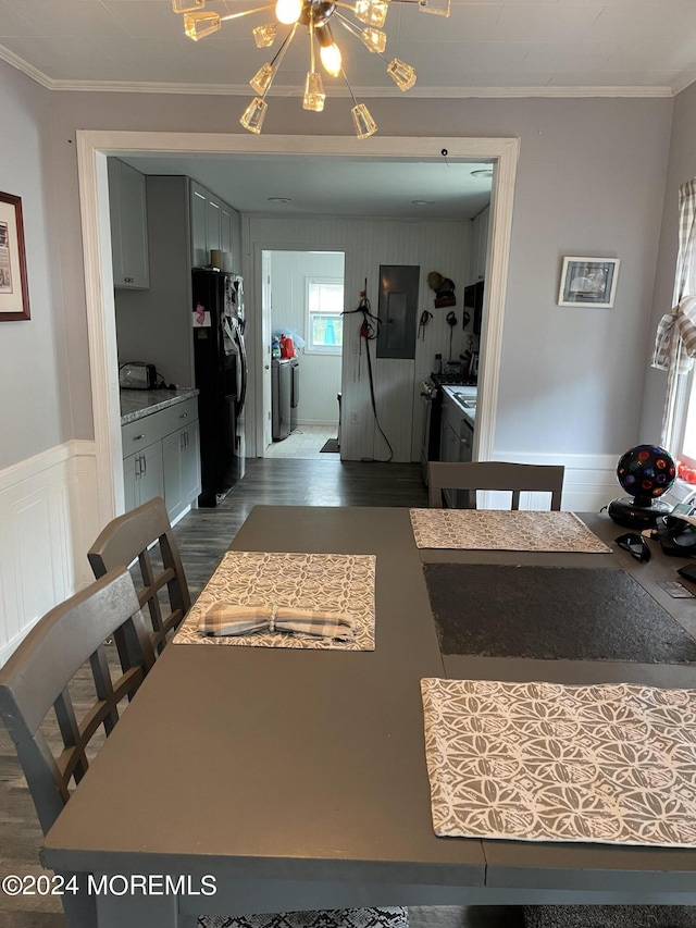 kitchen with dark wood finished floors, black fridge with ice dispenser, a wainscoted wall, ornamental molding, and washing machine and dryer