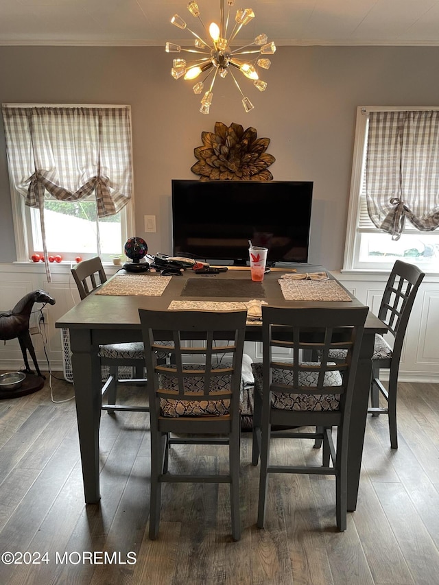 dining space with an inviting chandelier, ornamental molding, and wood finished floors