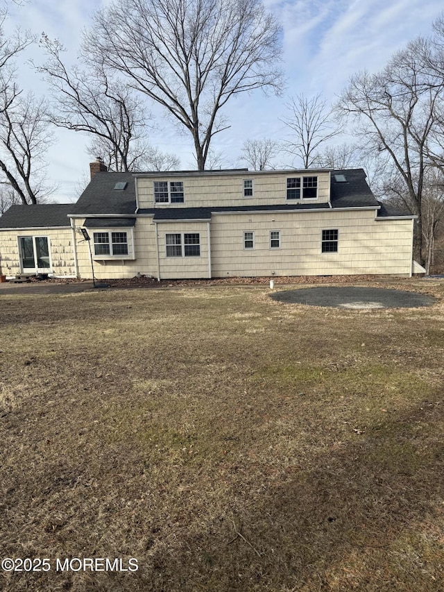 back of house featuring a yard and a chimney