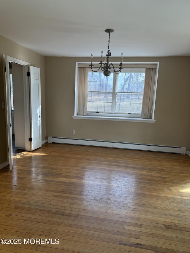 unfurnished dining area featuring an inviting chandelier, a baseboard heating unit, and wood finished floors