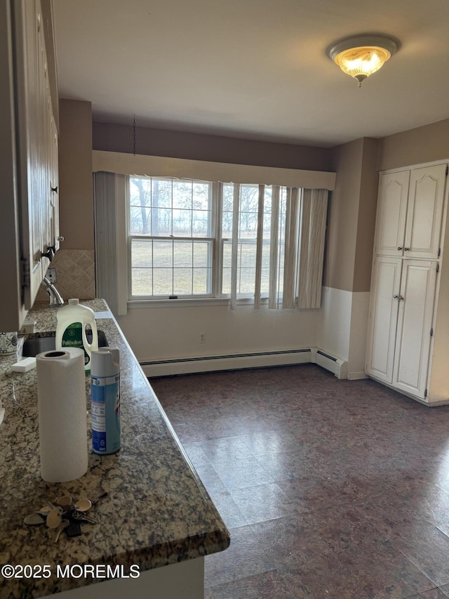 kitchen with a baseboard heating unit and white cabinetry