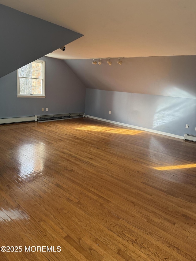 additional living space featuring baseboard heating, baseboards, vaulted ceiling, and wood finished floors