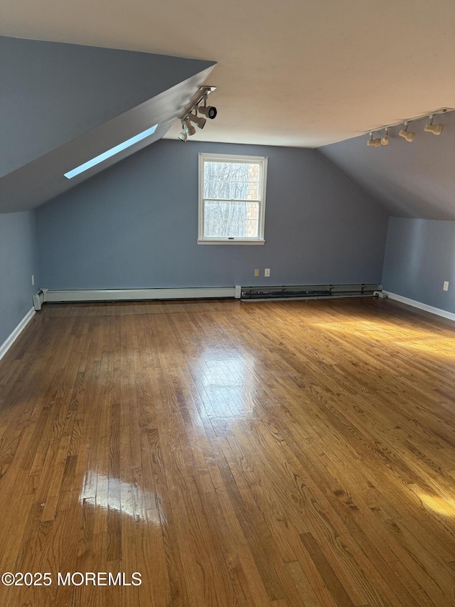 additional living space with vaulted ceiling, hardwood / wood-style flooring, and baseboards