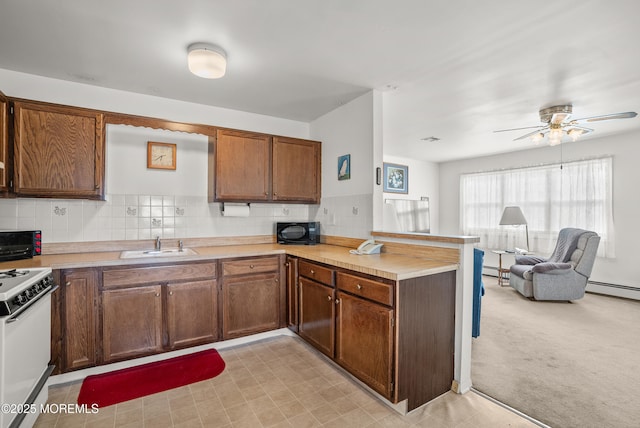 kitchen featuring white range with electric stovetop, open floor plan, a peninsula, black microwave, and a sink