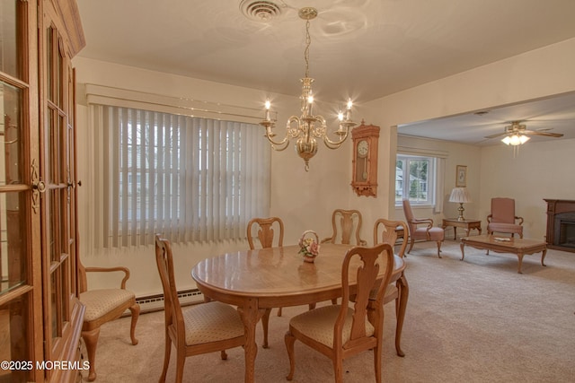 dining area featuring light colored carpet, a baseboard heating unit, ceiling fan with notable chandelier, a fireplace, and visible vents