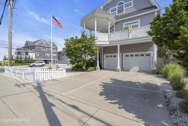 view of front of house with a garage, driveway, a balcony, and fence