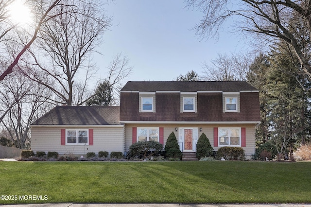 colonial inspired home with roof with shingles and a front yard