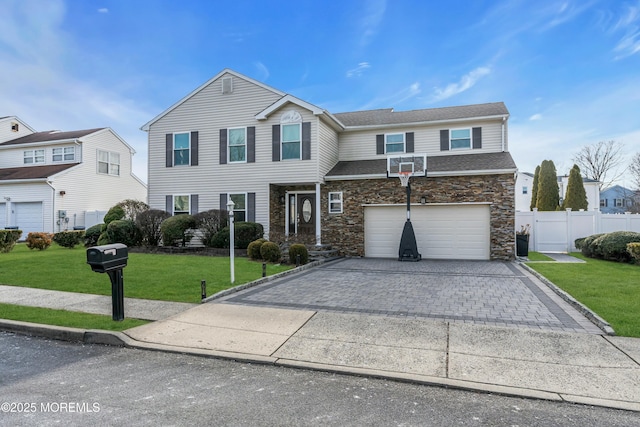 traditional-style home with stone siding, an attached garage, fence, decorative driveway, and a front yard