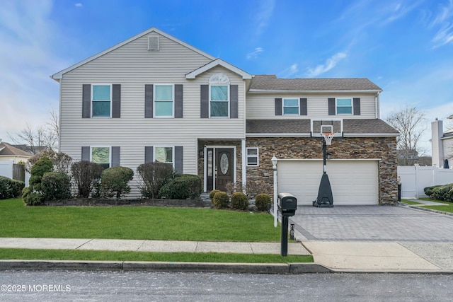 traditional home featuring a garage, fence, stone siding, decorative driveway, and a front yard