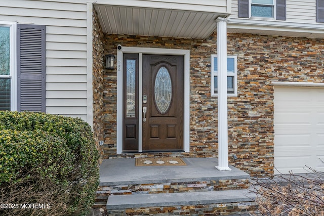 entrance to property featuring a garage and brick siding