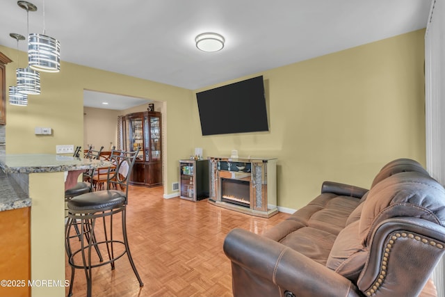 living area featuring a glass covered fireplace and baseboards