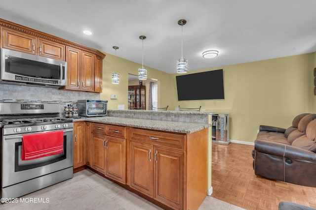 kitchen with light stone counters, brown cabinets, stainless steel appliances, decorative backsplash, and a peninsula