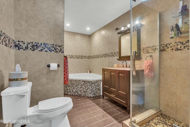 full bath with toilet, a garden tub, vanity, a shower stall, and tile walls