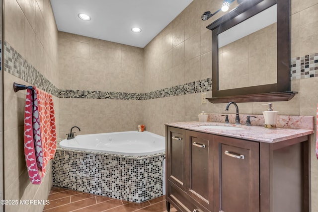 bathroom with a bath, tile walls, and vanity