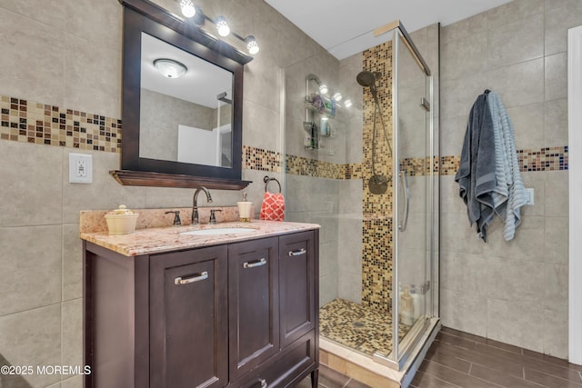 bathroom with a stall shower, vanity, and tile walls