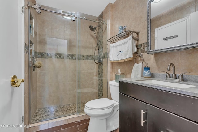 bathroom with tile walls, toilet, decorative backsplash, a stall shower, and vanity