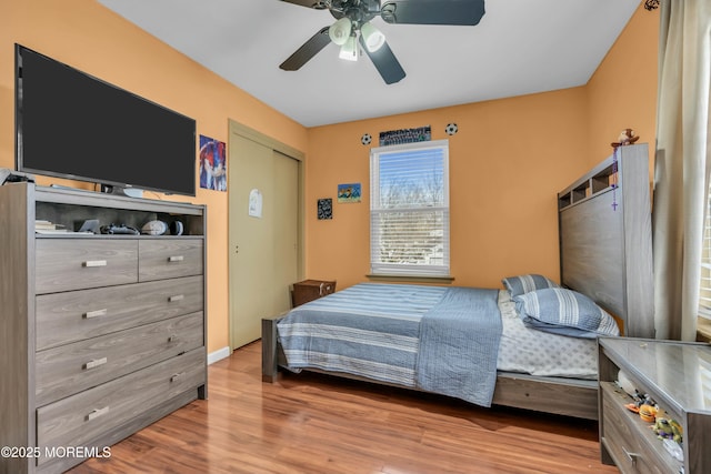 bedroom featuring ceiling fan, a closet, wood finished floors, and baseboards