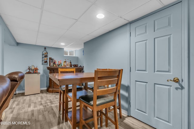 dining room featuring a dry bar, light wood finished floors, baseboards, a paneled ceiling, and recessed lighting