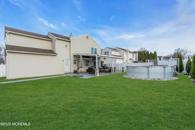 rear view of property with a patio, fence, a fenced in pool, and a yard