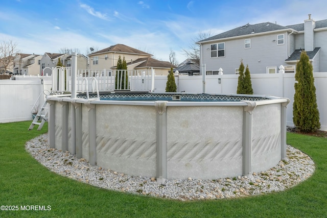 view of pool with a fenced backyard, a residential view, a lawn, and a fenced in pool