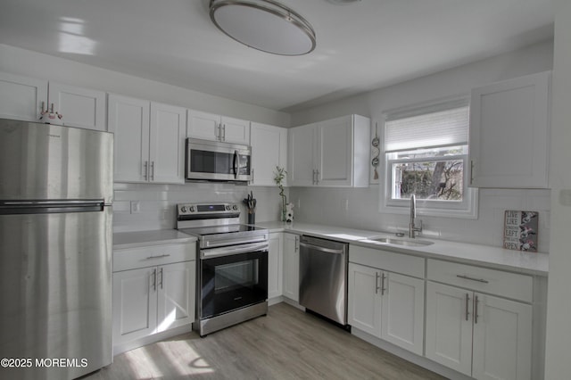 kitchen with appliances with stainless steel finishes, light countertops, white cabinets, and a sink