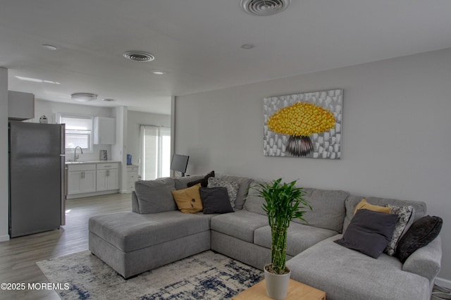 living room with light wood-style flooring and visible vents